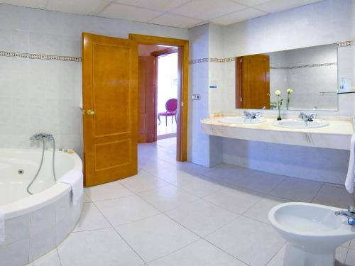 a bathroom with two sinks and a tub and a toilet at Magic Cristal Park in Benidorm