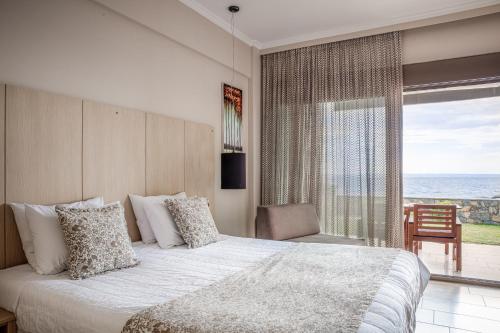 une chambre avec un lit avec vue sur l'océan dans l'établissement Royalty Suites Seaside, à Nikiti