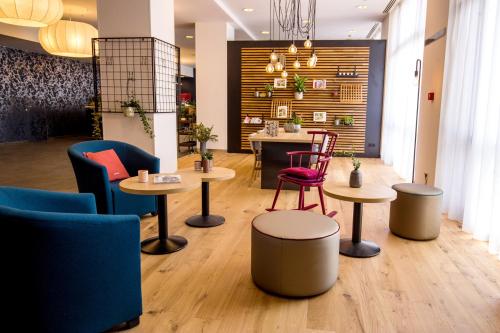 a lobby with tables and chairs and a counter at Vienna House Easy by Wyndham Bucharest Airport in Otopeni
