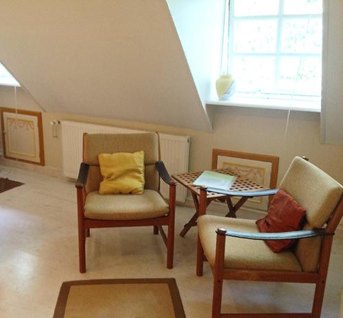 a living room with chairs and a table and a window at Myrehøj Bed & Breakfast in Eskebjerg