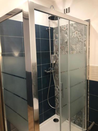 a glass shower in a bathroom with blue tiles at Shardan Guest House in Alghero