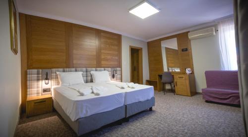 a bedroom with a large bed and a purple chair at Prince Cyril Hotel in Nesebar