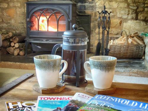 two cups of coffee sitting on a table in front of a fireplace at Century House in Moreton in Marsh