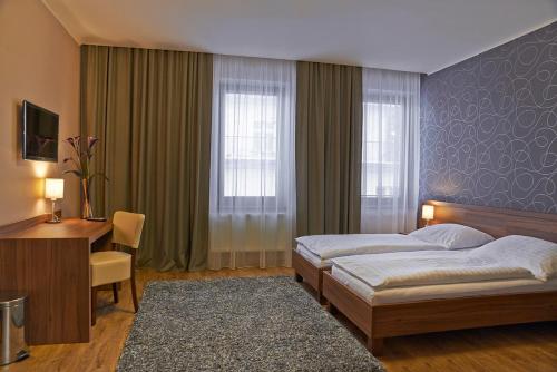 a hotel room with two beds and a desk and a desk at Penzion Club in Skalica