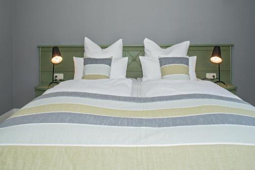 a large white bed with several pillows on it at Upstalsboom Hotel Trassenheide in Trassenheide