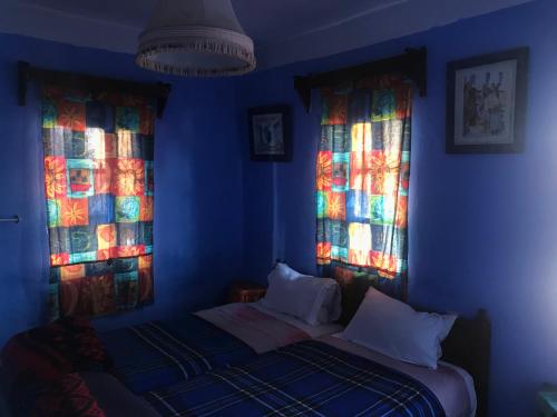 una camera blu con due finestre e un letto di Hotel Asmara a Chefchaouen
