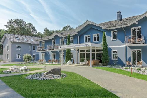 a large blue house with a yard at Upstalsboom Hotel Trassenheide in Trassenheide