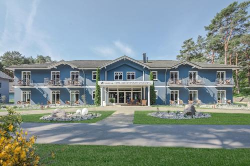 a large blue house with a yard at Upstalsboom Hotel Trassenheide in Trassenheide