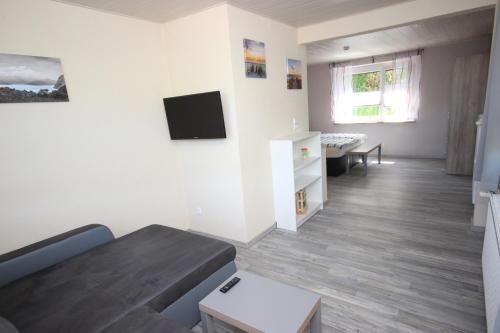 a living room with a couch and a tv on the wall at Ferienwohnung Pedall in Bischofsgrün