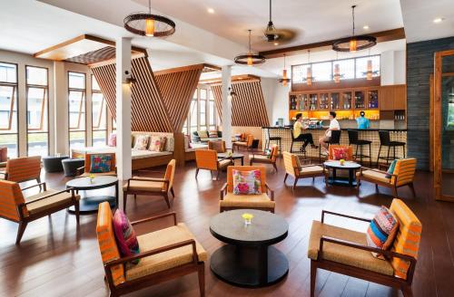 a lobby with tables and chairs and people in the background at Deevana Plaza Krabi Aonang - SHA Extra Plus in Ao Nang Beach