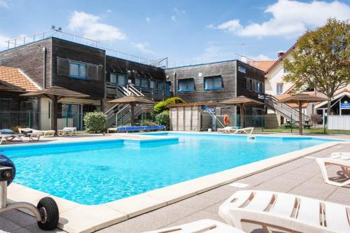 une piscine devant un immeuble dans l'établissement LE SOLEIL DE JADE village vacances, à Préfailles