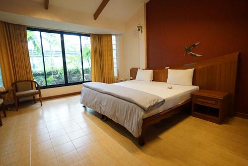 a bedroom with a large bed and a large window at Country Lake View Hotel in Suphan Buri