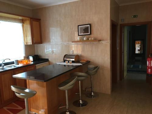 a kitchen with a counter and stools in it at Casa do Carroça in Terreiros