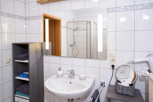 a white bathroom with a sink and a mirror at Ferienwohnung Panorama-Blick in Ulmen