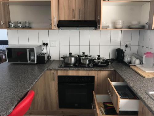 a kitchen with two pots on a stove with a microwave at Home Inn Self-Catering in Windhoek