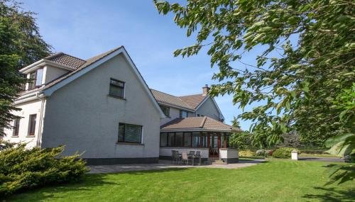 a large white house with a grass yard at Keef Halla Country House in Crumlin