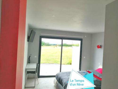 a room with a bed and a sliding glass door at Le Temps d'un Rêve in Eauze
