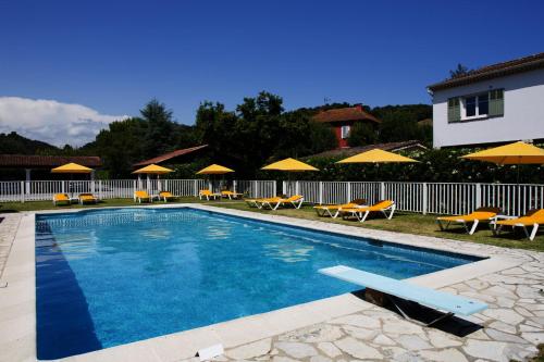 a swimming pool with chairs and umbrellas next to a house at Hotel du Bosquet in Pégomas