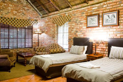 a bedroom with two beds and a brick wall at Elgro River Lodge in Potchefstroom