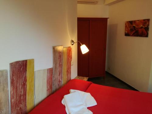 una camera con letto rosso, lampada e dipinti di Appartamento Via Signorini a Riomaggiore