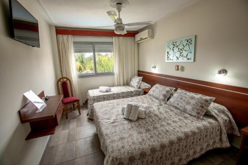 a hotel room with two beds and a desk at Hotel Termasol in Termas de Río Hondo