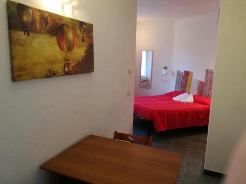 Habitación pequeña con cama roja y mesa. en Appartamento Via Signorini, en Riomaggiore