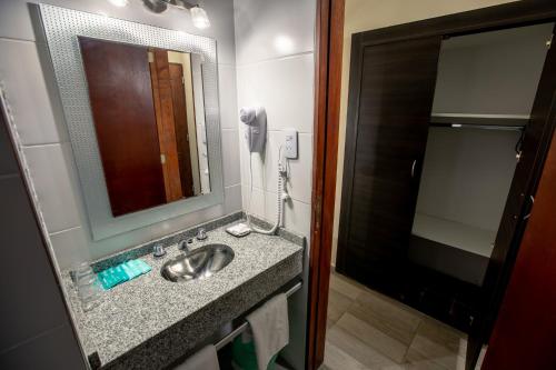 a bathroom with a sink with a mirror and a phone at Hotel Termasol in Termas de Río Hondo