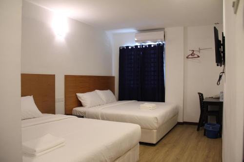 two beds in a small room with a desk and a window at Amanjaya Hotel in Sungai Petani