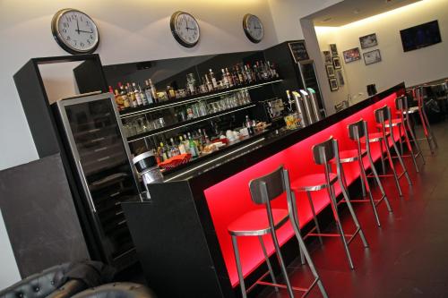 a bar with red chairs and clocks on the wall at Hotel Grey in Luxembourg