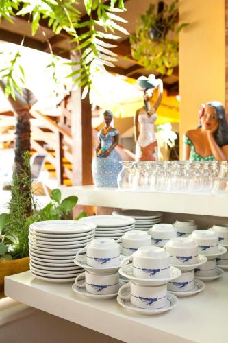 a shelf with plates and other dishes on it at Pousada Camburioca in Camburi