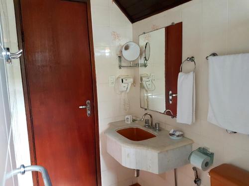 La salle de bains est pourvue d'un lavabo et d'un miroir. dans l'établissement Hotel Akropolis, à Serra Negra