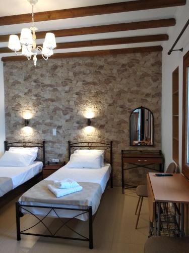 a bedroom with two beds and a stone wall at Casa del centro in Kardámyla