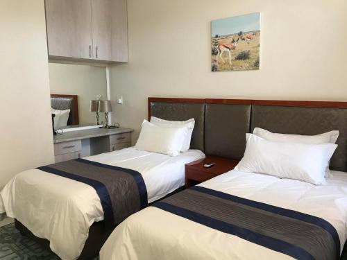 a hotel room with two beds and a sink at Home Inn Self-Catering in Windhoek
