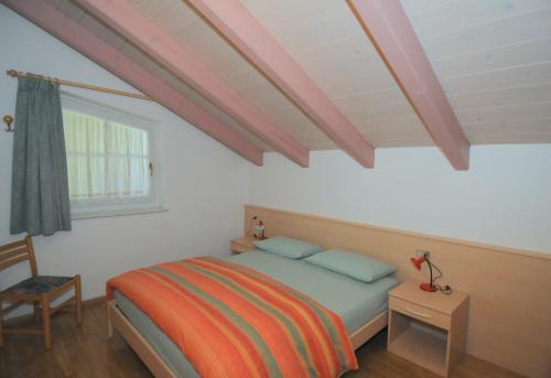 a bedroom with a bed and a table and a window at Casa El Tobià in Pozza di Fassa