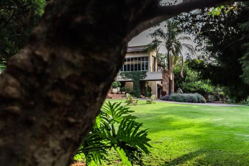 a building with a green yard with benches in front of it at Hagios House in Pretoria