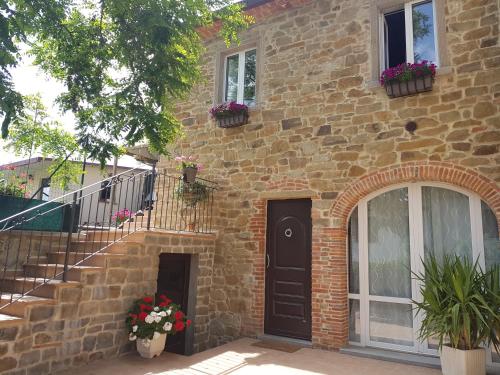 a brick house with a black door and flower boxes at Vicus House in Viciomaggio