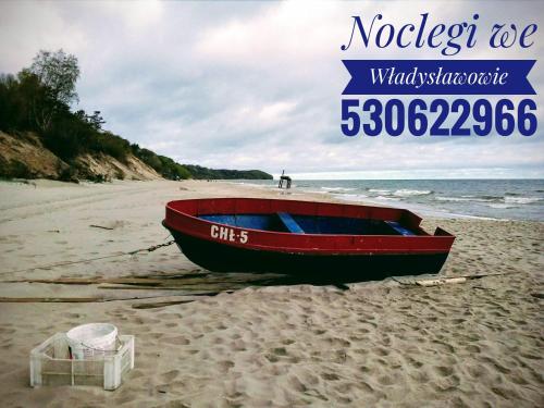 un barco rojo sentado en una playa de arena en Satori, en Władysławowo