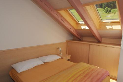 a bedroom with a bed and two windows at Casa El Tobià in Pozza di Fassa