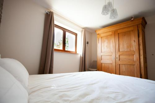 um quarto com uma cama branca e uma porta de madeira em Le gîte des Histoires em Kientzheim