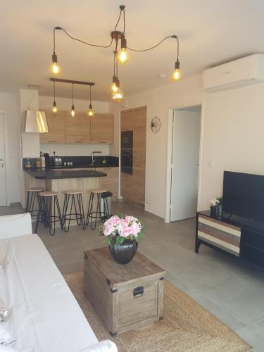 un salon avec une table avec des fleurs dessus dans l'établissement T2 NEUF AVEC TERRASSE - PROCHE DES PLAGES, à Saint-Cyr-sur-Mer