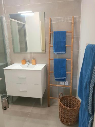 La salle de bains est pourvue d'un lavabo et d'une étagère avec des serviettes bleues. dans l'établissement T2 NEUF AVEC TERRASSE - PROCHE DES PLAGES, à Saint-Cyr-sur-Mer