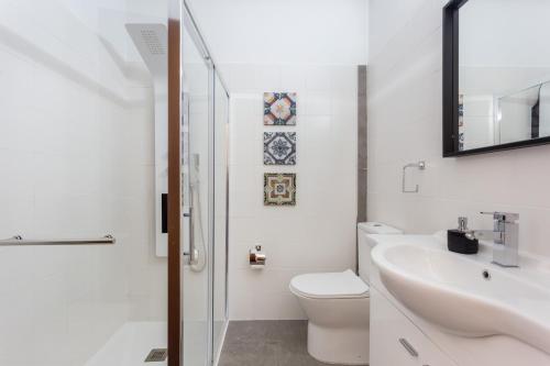 a white bathroom with a toilet and a sink at Casa Furneaux by Seewest in Lagos