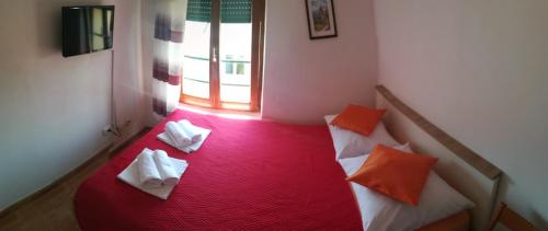 a room with a red bed with two towels on it at Apartments Knežić in Igrane