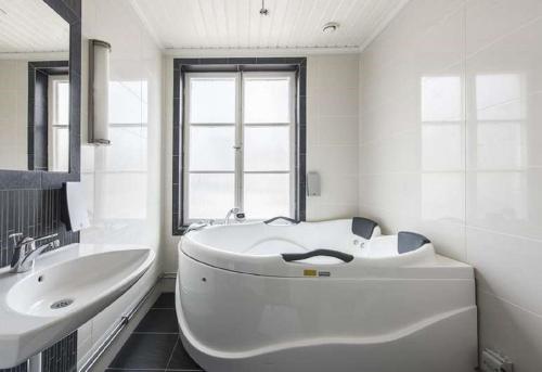 La salle de bains blanche est pourvue d'une baignoire et d'un lavabo. dans l'établissement Hedemora Stadshotell, à Hedemora