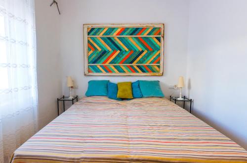 a bedroom with a large bed with a painting on the wall at la casa de dias soleados in Denia