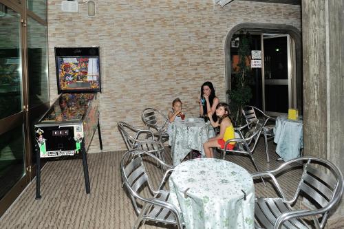 a woman and two children sitting at a table with a video game at Hotel Lidia in Alba Adriatica