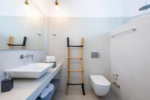 Un baño con lavabo, inodoro y espejo. en Agkairia´s House, en Angairiá