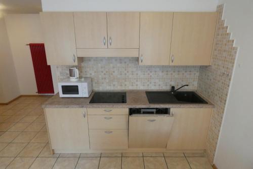 a small kitchen with a sink and a microwave at Casa El Tobià in Pozza di Fassa