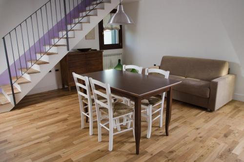 a dining room table with white chairs and a couch at Agriturismo Monte Scala in Taglio di Po