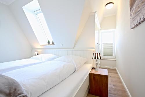 a white bedroom with a bed and two windows at Villa Petersen "Himmel & Meer" in Wangerooge